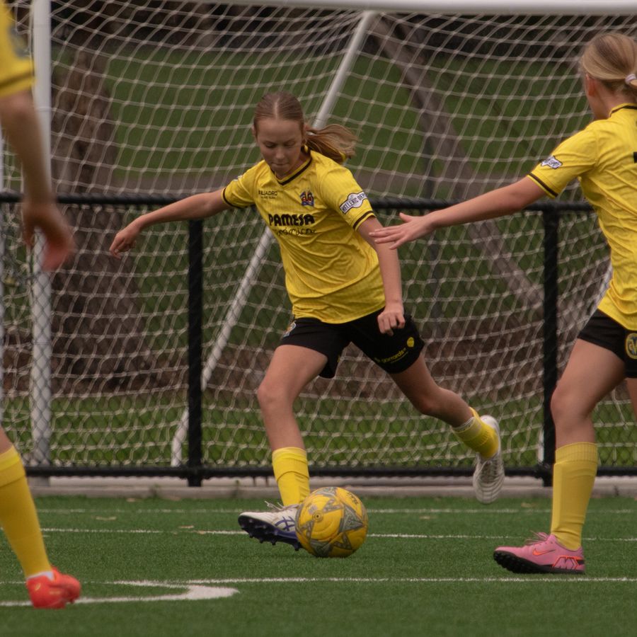 Community team player striking the ball with teammates around her